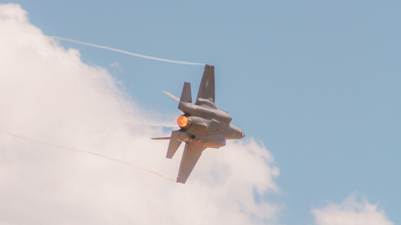 Image Credit: A fighter jet flying through a cloudy blue sky — Heber Davis