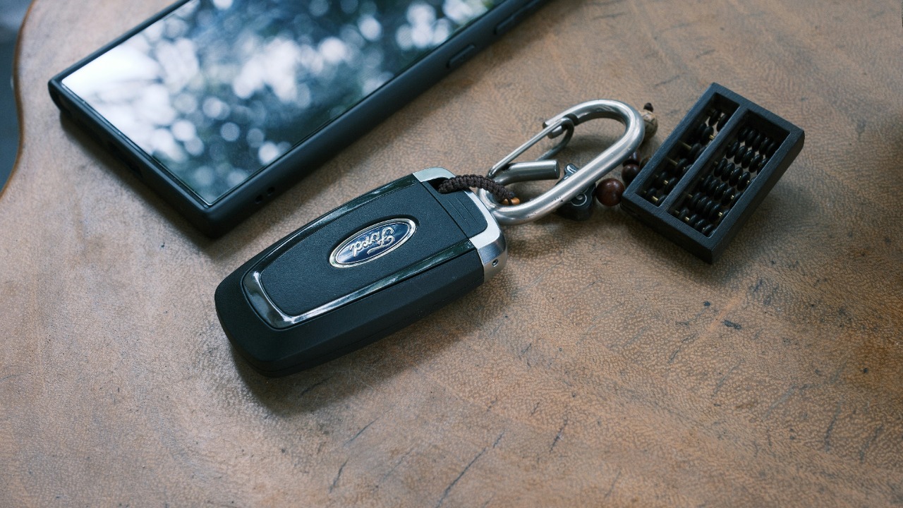 Car key, phone, and keychain on a wooden surface. — Duc Van