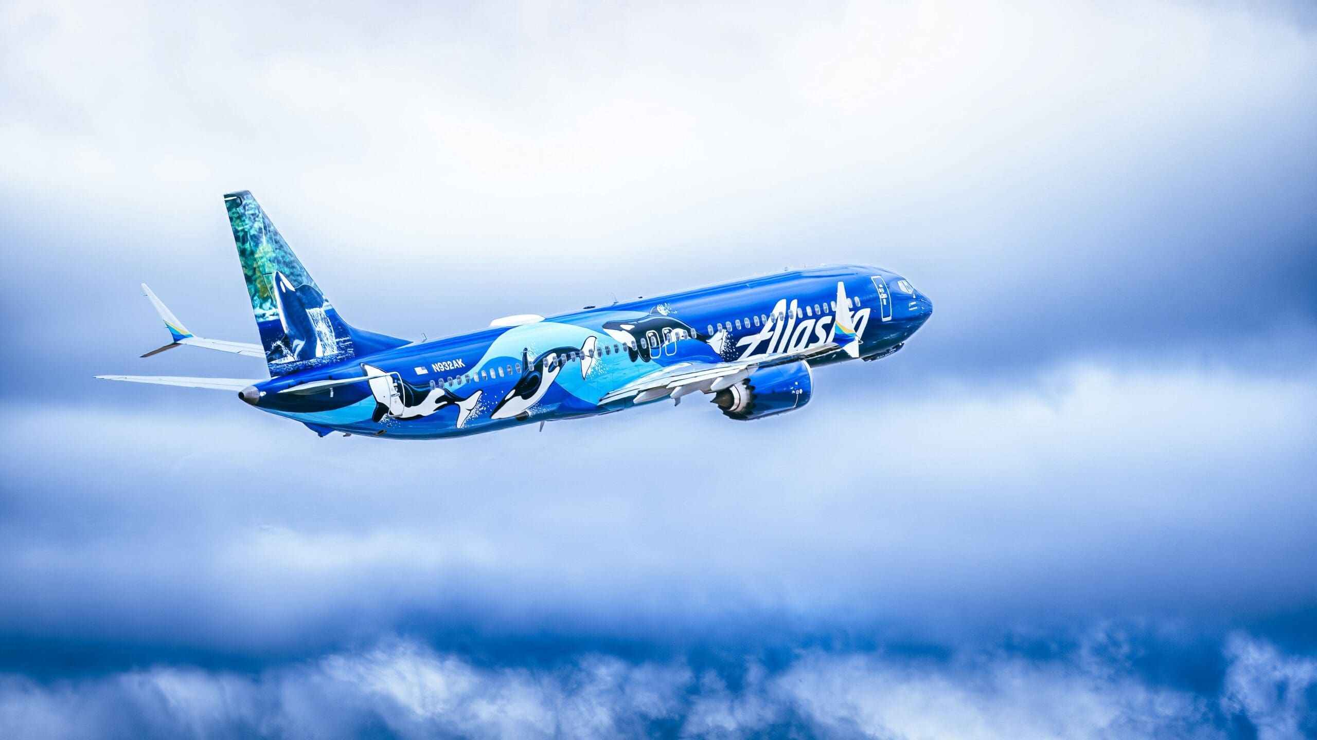 Alaska airlines plane soaring through the cloudy sky.