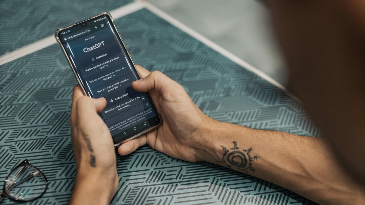 Man interacting with ChatGPT app on smartphone, showcasing technology in daily life.