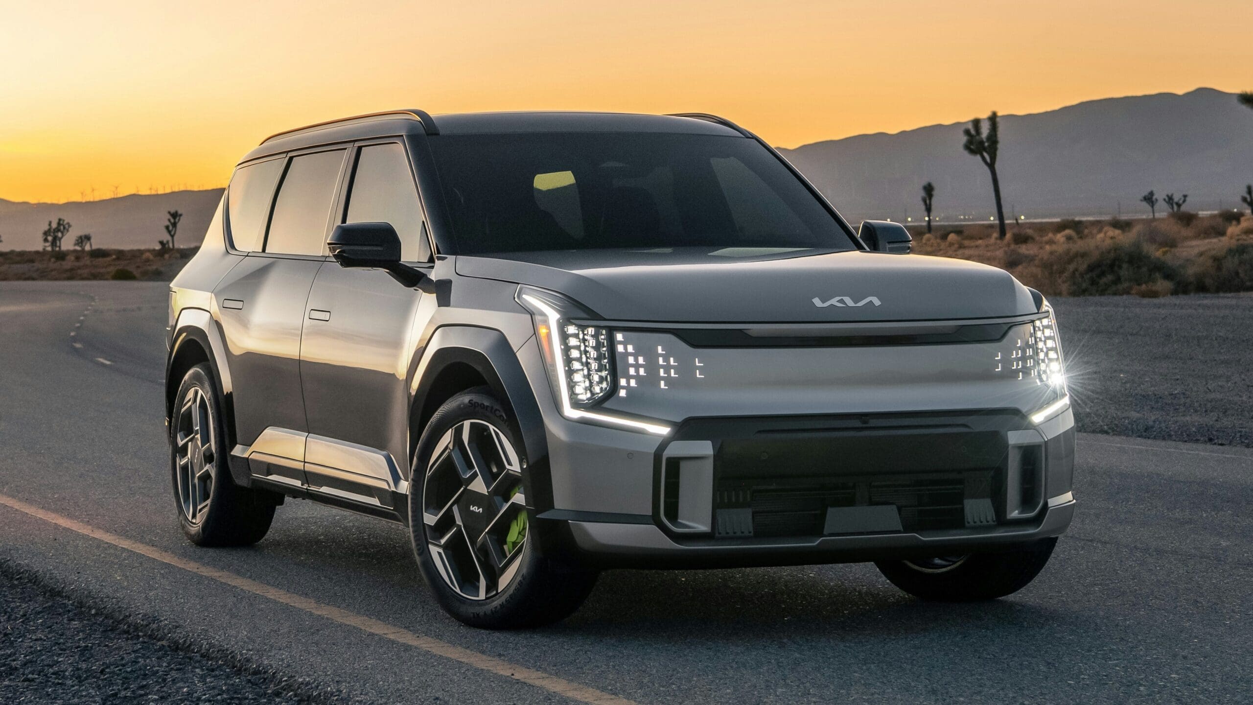 A silver suv driving down a road at sunset