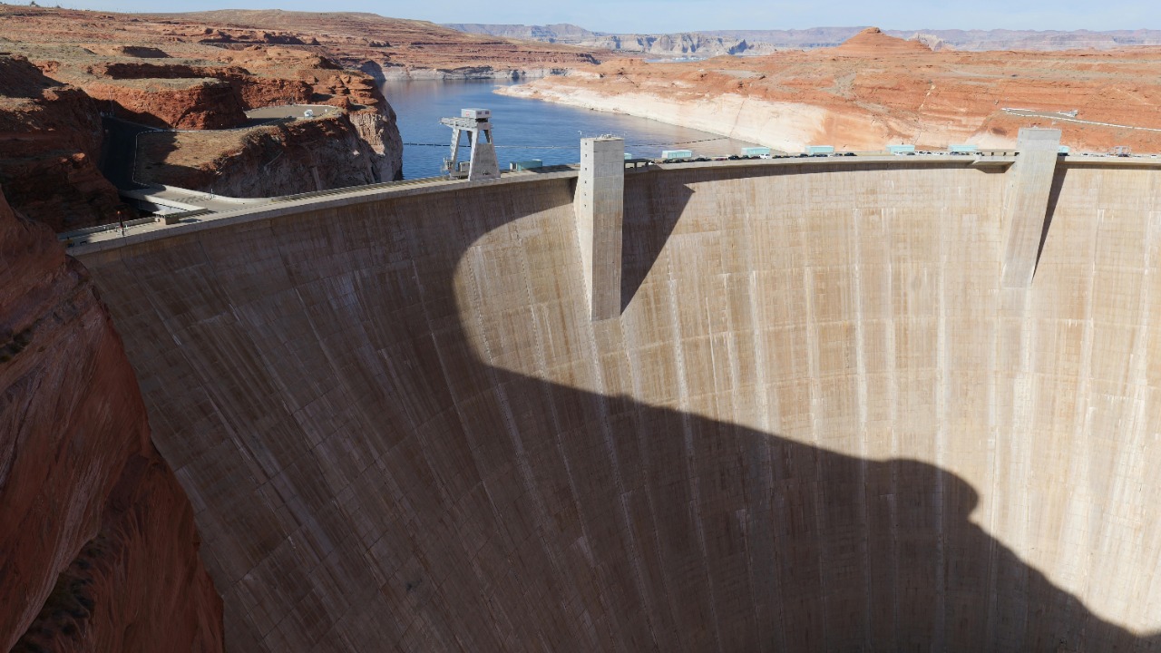 A stunning aerial shot showcasing Glen Canyon Dam and the Colorado River under sunlight.