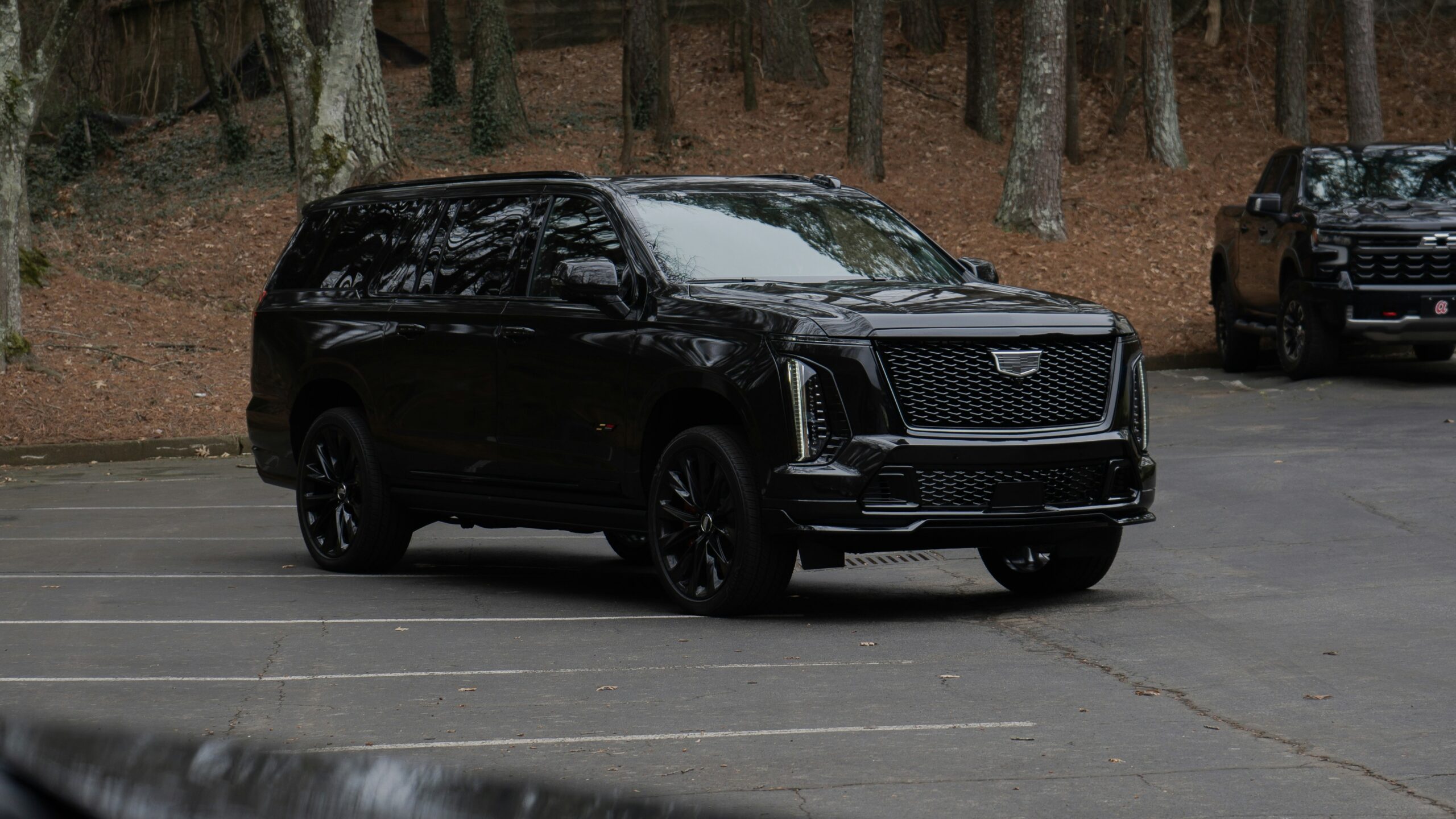 A black cadillac escalade parked in a lot. A black cadillac escalade parked in a lot.