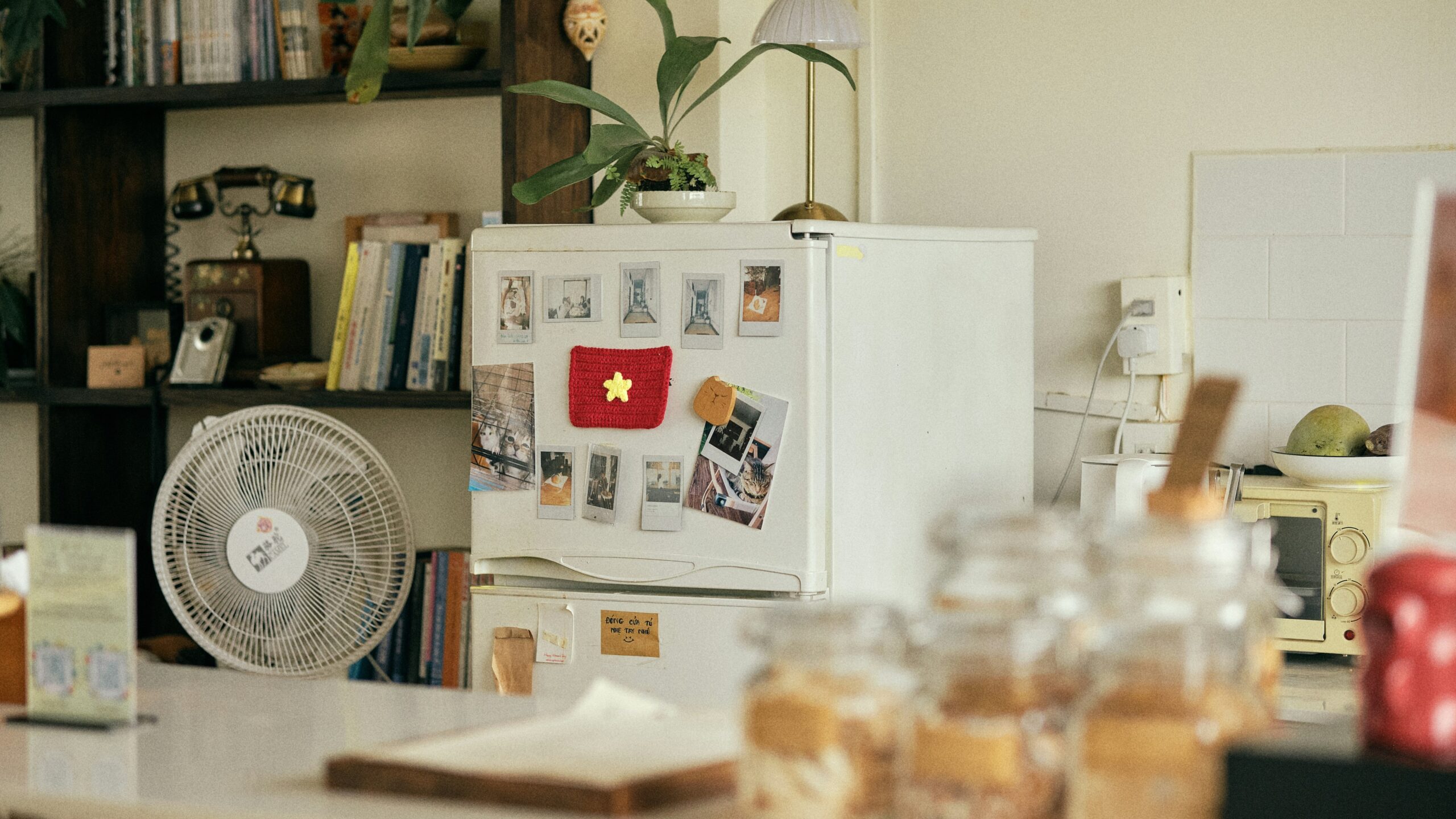 Refrigerator with flag magnet, fan, and jars on a counter.